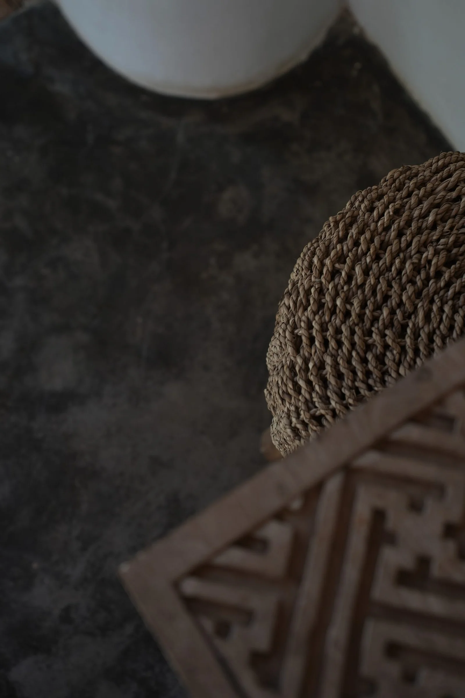 Woven basket and carved timber screen on a polished concrete floor