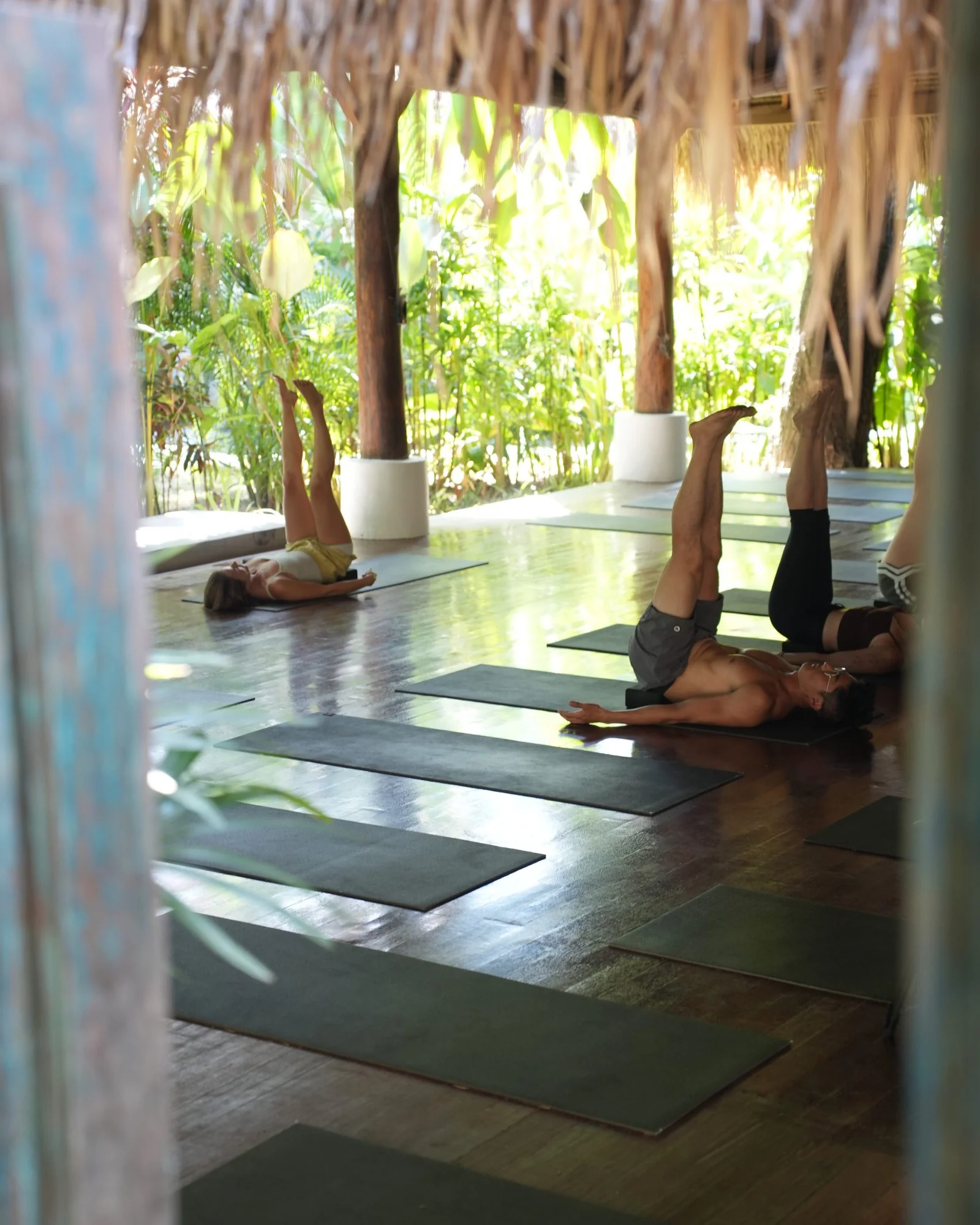 Yoga class in shoulder stand, seen through the shala doors
