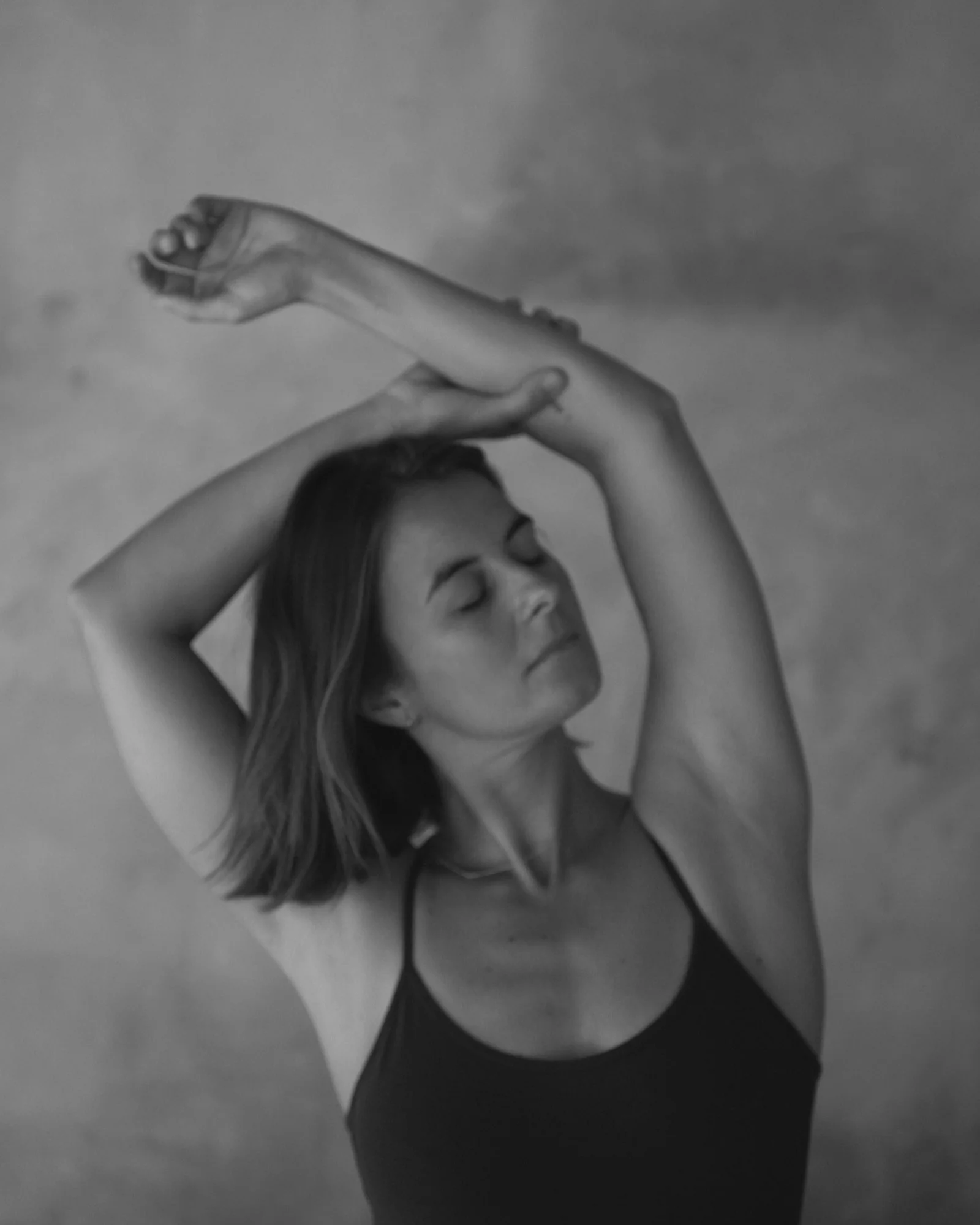 Black and white portrait of a woman stretching her arms overhead