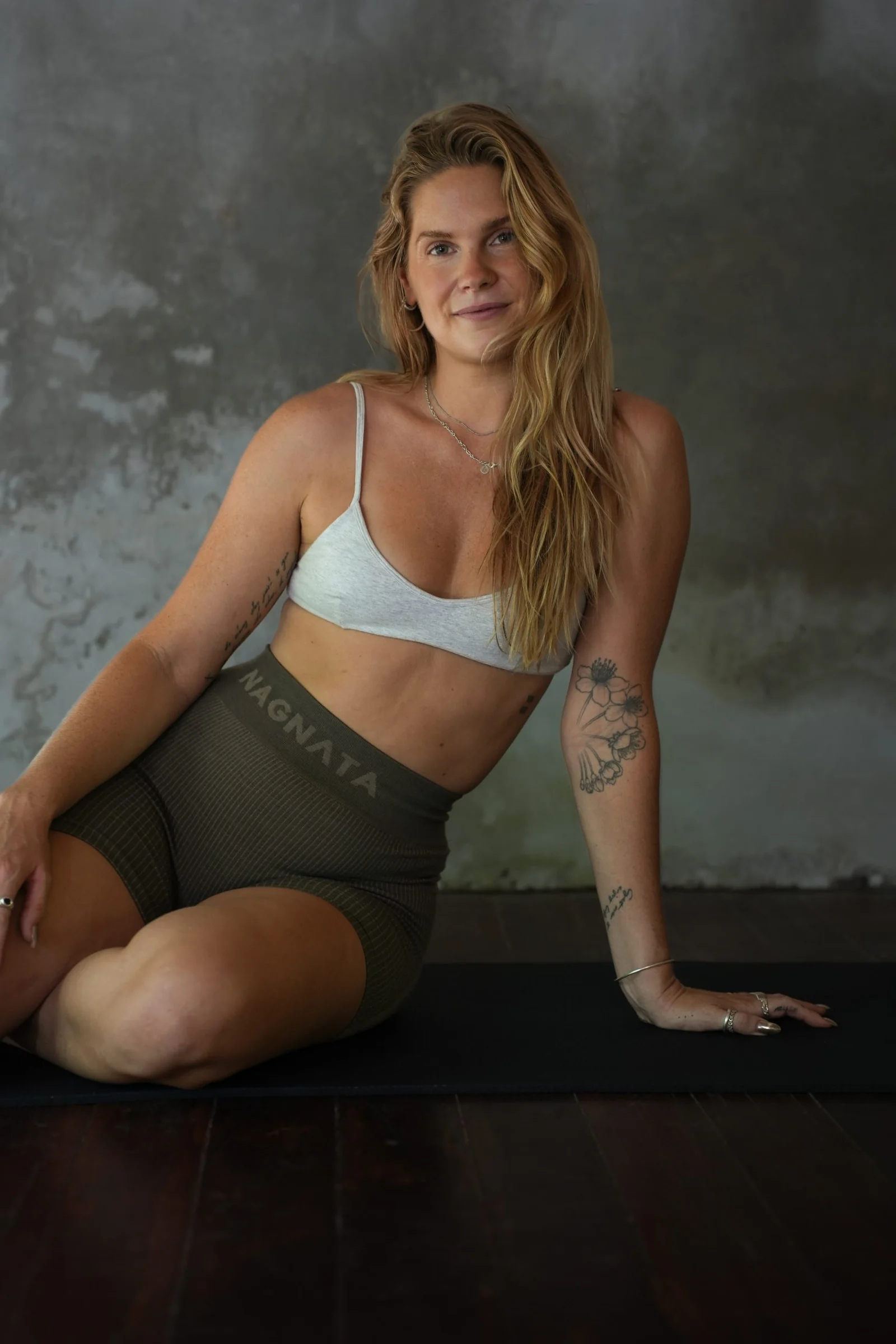 Smiling woman seated on a yoga mat in the studio at Mana Eco Retreat