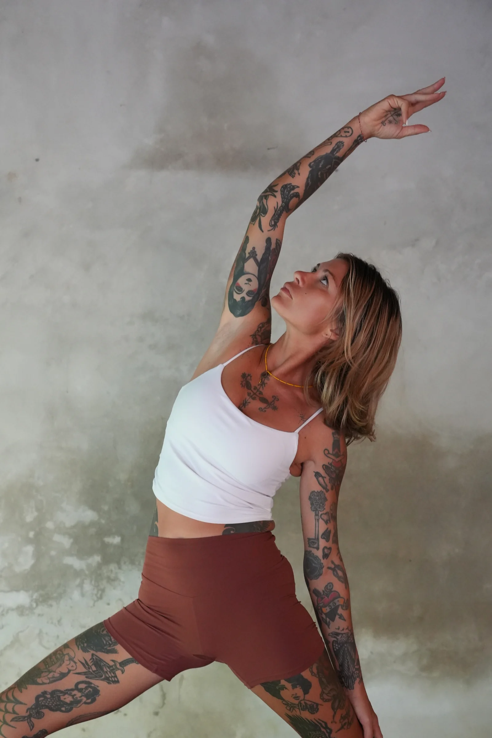 Yoga teacher in an extended side angle pose against a textured concrete wall