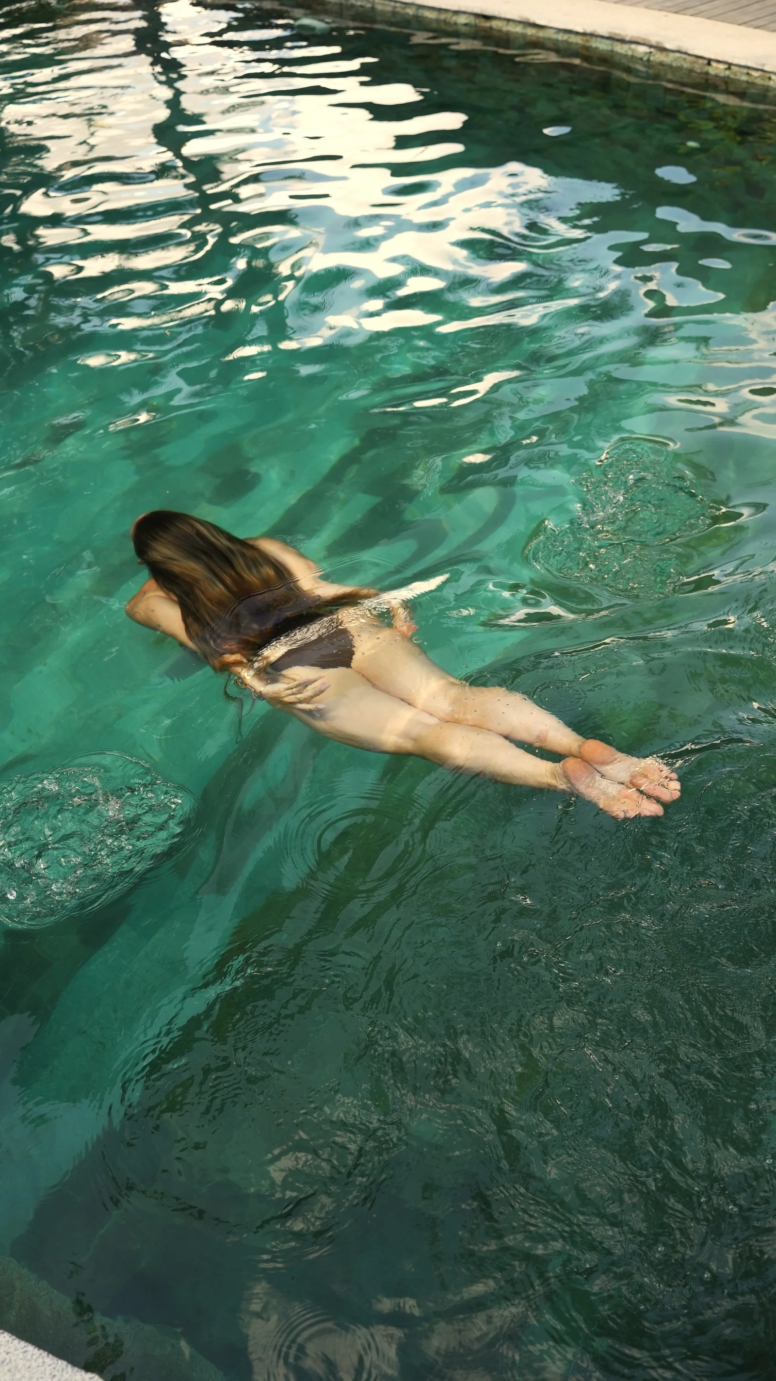 Woman swimming in the green pool at Mana Eco Retreat, seen from above