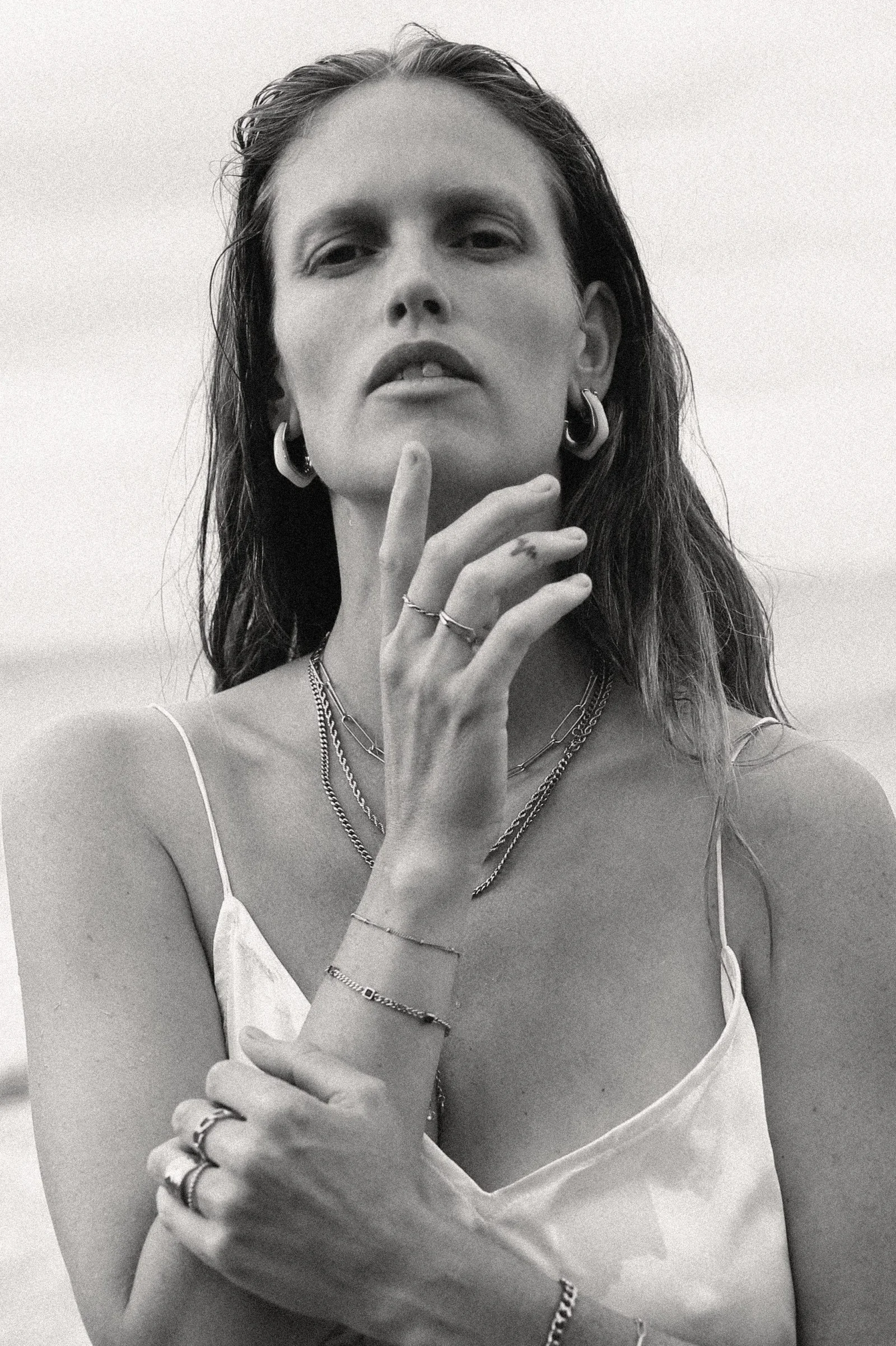 Black and white film portrait of a model wearing gold hoops and layered bracelets
