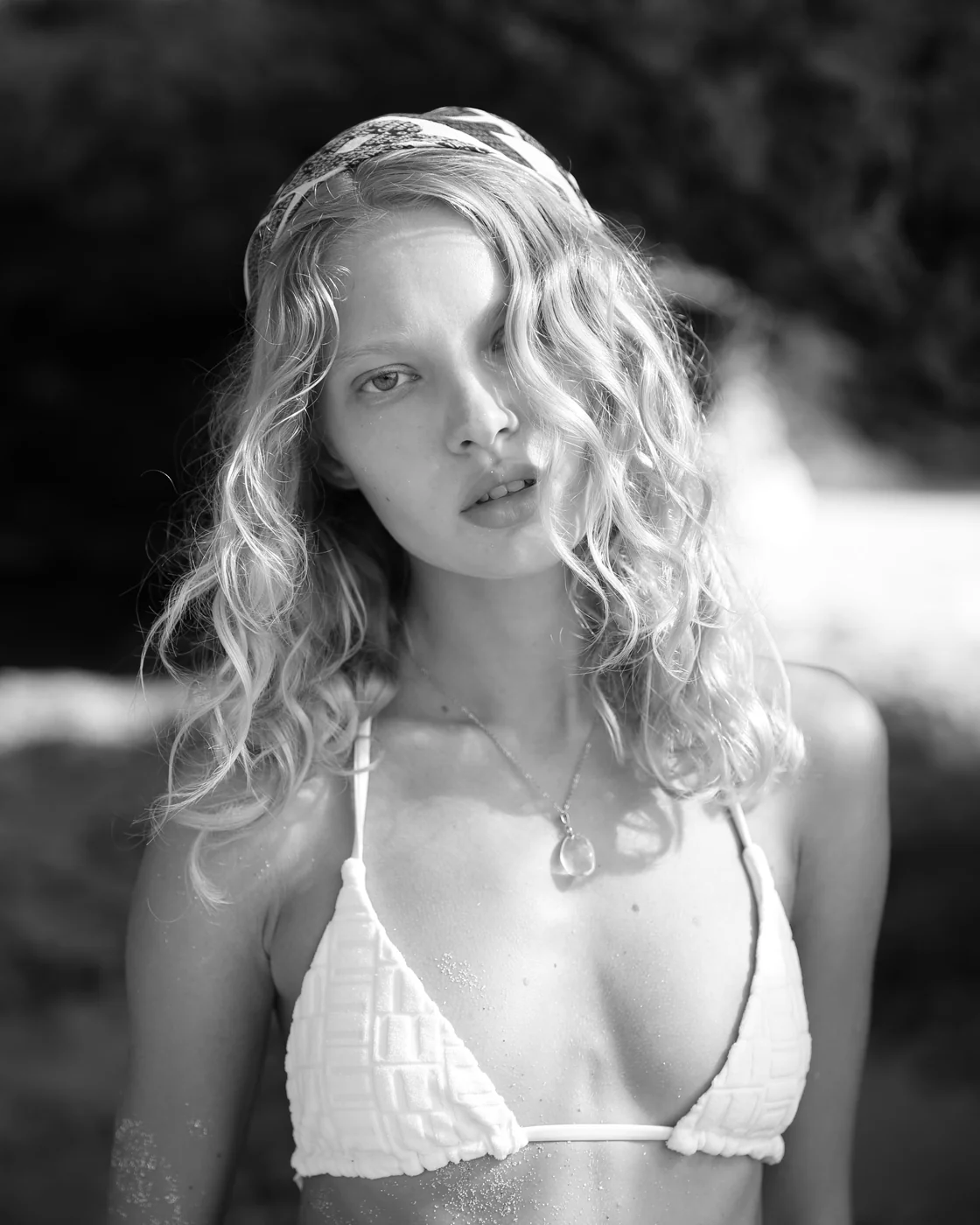 Black and white close-up of a model with wet hair in a textured bikini top